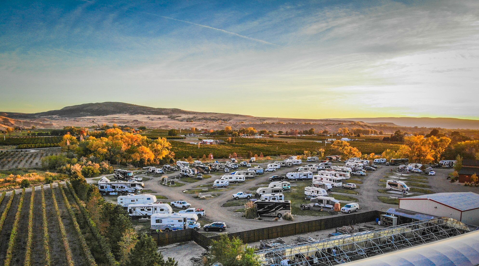 Aerial view of Palisade Basecamp RV Resort with a sunset in the background
